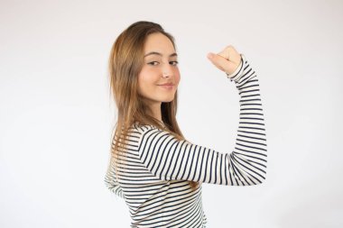 Güçlü ve enerjik. Kolunda pazı gösteren güzel, genç, esmer bir kadın. Sarı arka planlı renkli bir stüdyo portresi.