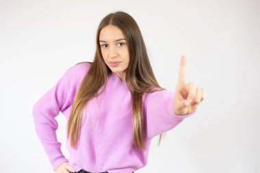 Pembe kazaklı genç kız beyaz arka planı işaret ediyor.