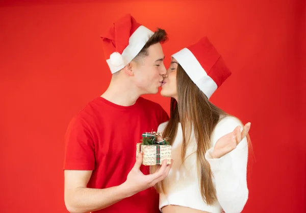 Menino Dando Presente Namorada Enquanto Beijam Vestindo Chapéu Papai Noel — Fotografia de Stock