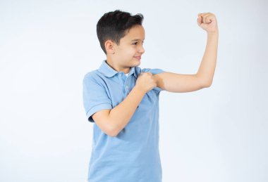 Çocuk beyaz arka planda kol kaslarını gösteriyor..