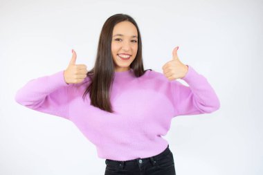 Gülümseyen güzel genç kadın beyaz arka planda baş parmak gösteriyor.