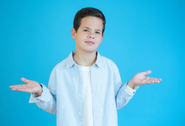 Sıradan beyaz tişörtlü, kafası karışık, kolları ve elleri havada bir çocuk. şüphe kavramı.