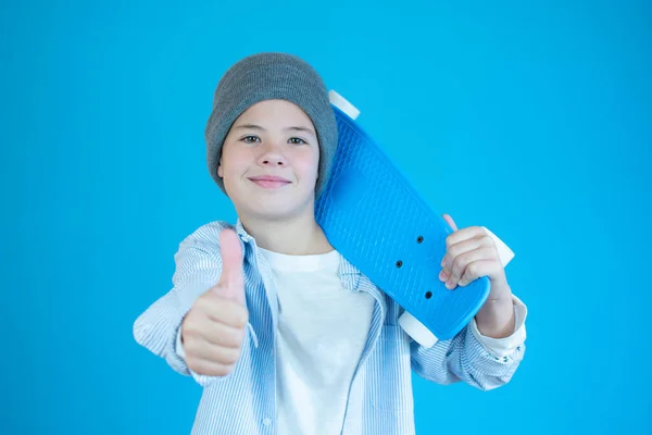 Χαμογελώντας Αγόρι Κρατώντας Ένα Skateboard Τον Αντίχειρα Πάνω Από Μπλε — Φωτογραφία Αρχείου