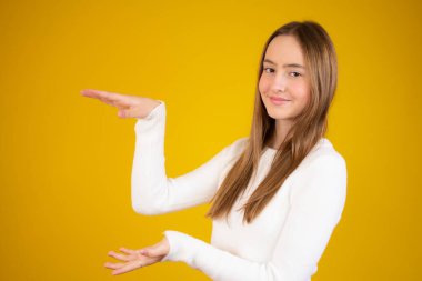 Gündelik giysiler giymiş genç beyaz bir kız avuçlarını açıp fotokopi alanını gösteriyor, gülümseyerek mutlu bir şekilde gülümsüyor.