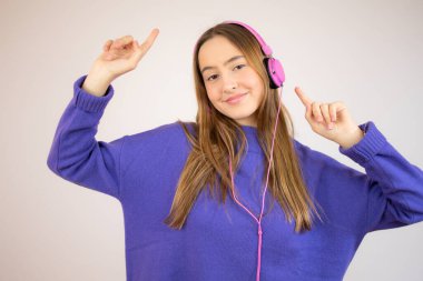 Kulaklıklı, beyaz arka planda müzik dinleyen güzel genç bir kadın.