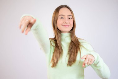 Genç ve güzel bir kız iki baş parmağını kaldırmış, beyaz üzerinde izole edilmiş.