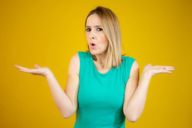 Yeşil elbise giyen, elleri ve kolları havada, kafası karışmış genç bir kadın. Şüphe kavramı.