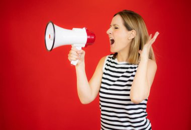 Kırmızı arka planda hoparlör kullanan güzel bir genç kadının portresi..