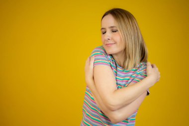 Çizgili tişörtlü, kendine sarılan güzel bir kadının portresi. Bencil duygu kavramı.