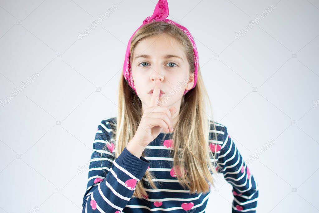 Closeup portrait of blonde girl putting finger up to lips isolated on white background