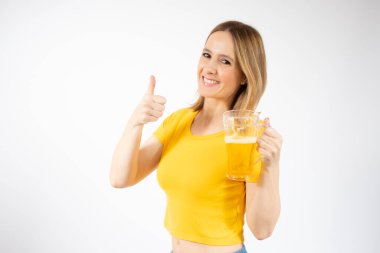 Bira dolu bir bardak tutan ve beyaz arka planda gülümseyen neşeli genç bir kadın.