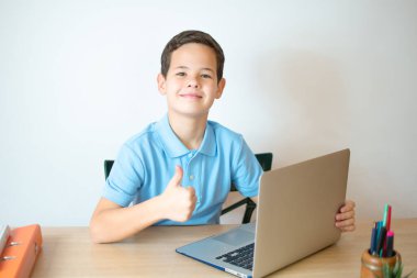 Sınıfta gülümseyen ve dizüstü bilgisayar izleyen genç bir çocuk. Evinde bilgisayar öğrenmek için daktilo yazan genç bir çocuk..