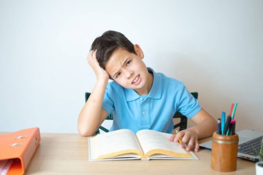 Genç bir çocuk ödevini yapıp ders kitabını okuyor..