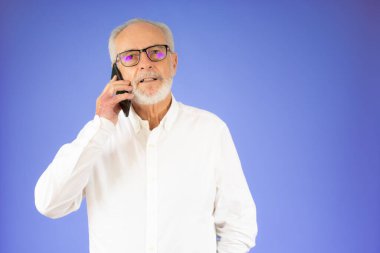 Kafkasyalı kıdemli bir adam akıllı telefondan neşeli ve mutlu bir yüzle konuşuyor.