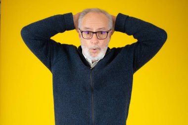 Sarı arka planda, yüzünde şaşkın bir ifade olan son sınıf öğrencisi.