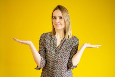 İzole edilmiş arka plan bilgisiz ve elleri ve kolları havada, kafası karışmış genç ve güzel bir kadın. Şüphe kavramı.