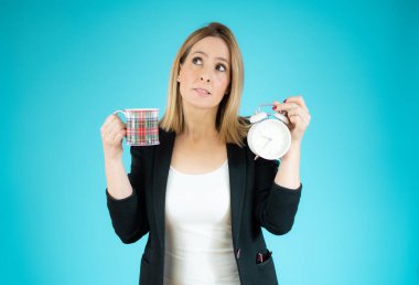 İş kadını elinde çalar saat ve yeşil arka planda bir fincan kahve tutuyor..