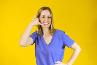 Genç bir kadın bana işaret veriyor ve sarı arka planda gülümsüyor..