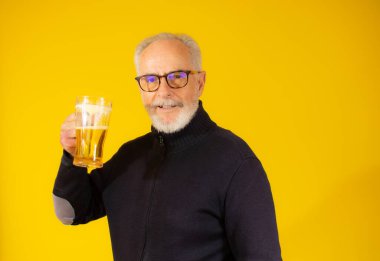 Üst düzey yakışıklı adam izole edilmiş sarı arka planda duran bira kavanozunu içiyor.