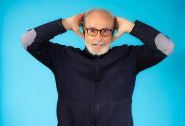 Sıradan süveter giyen yaşlı bir adam mavi arka planda izole edilmiş.