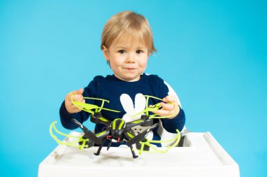 Bebek oturuyor ve mavi arka planda bir dron tutuyor..