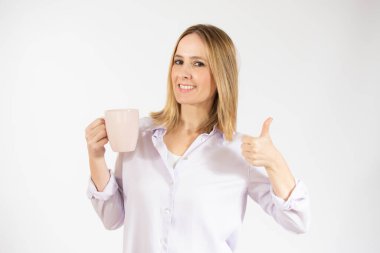 Genç bir kadın, izole edilmiş beyaz arka planda bir fincan sıcak kahve içiyor.