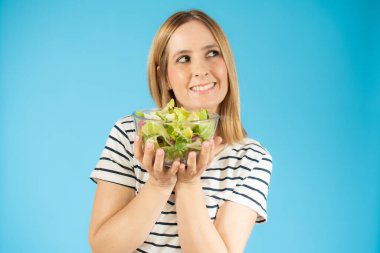 Kadın diyet portresi. Elinde yeşil salata tutan genç bir kadın. İzole edilmiş portre.
