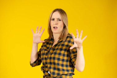 Korkmuş genç bir kadın sarı arka planda izole edilmiş.