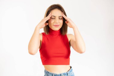 Ciddi bir beyaz kadının parmaklarını şakaklarına bastırıp konsantre ve odaklanmış ifadesini çektiği bir stüdyo fotoğrafı.