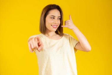 Sarı arka planda izole edilmiş güzel genç bir bayanın jesti diyebilirsin..