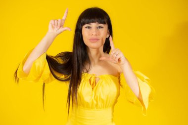 Mutlu kadın sarı arka planda parmakları izole bir çerçeve yapıyor.