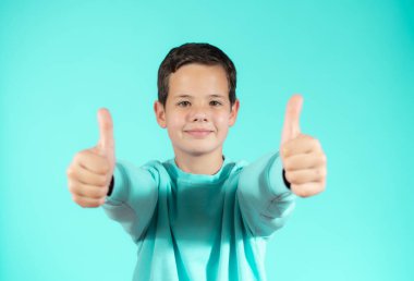 Yeşil arka planda izole edilmiş neşeli çocuk portresi. 10 yaşında bir çocuk işaret ediyor. Çocuk parmaklarıyla yukarı doğru işaret ediyor. Neşeli çocuk bir şeyler gösteriyor.