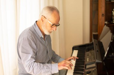 İşten emekli olduktan sonra evinin oturma odasında piyano çalmaya çalışan bir adam..