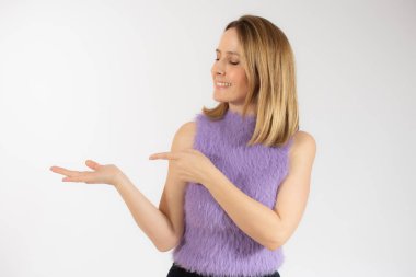 İzole edilmiş beyaz arka planda genç bir kadın parmaklarını kenarı işaret ediyor.