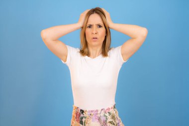 Front view of pensive pretty woman isolated over blue background.