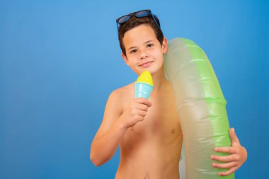 Child on summer vacation eating ice cream on isolated blue background