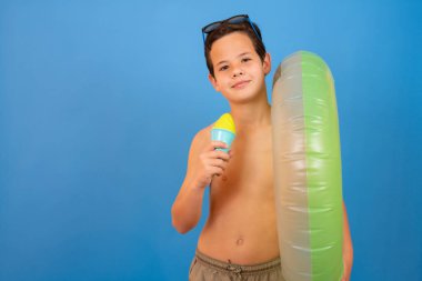 Child on summer vacation eating ice cream on isolated blue background