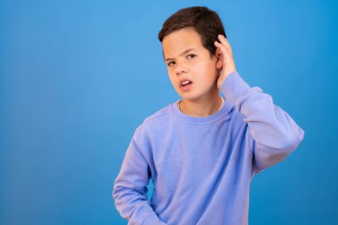 Konsantre olmuş genç bir çocuk bir şeyler duymaya çalışıyor.