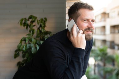 Genç adam dışarıda duruyor, telefonda konuşuyor..