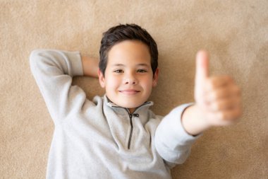 Küçük mutlu çocuğun baş parmağıyla yerde yatışı.