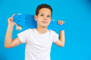 Mavi arka planda izole edilmiş kaykay tutan genç..