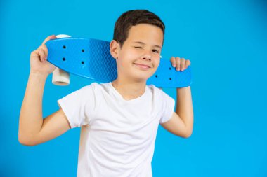 Mavi arka planda izole edilmiş kaykay tutan genç..