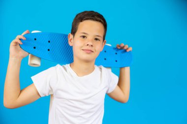 Mavi arka planda izole edilmiş kaykay tutan genç..