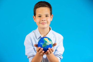 School boy holding a world globe isolated over blue background