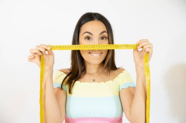 Elinde mezura tutan mutlu genç bir kadının yakın plan portresi.