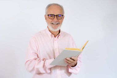 Beyaz arka plan üzerine kitap okuyan yaşlı bir adamın stüdyo fotoğrafı.