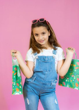 Pembe arka planda izole edilmiş alışveriş torbaları tutan tatlı İspanyol kız.