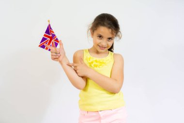 İngiliz bayrağı tutan gülümseyen küçük bir kız. İngilizce öğren. Uluslararası dil okulu konsepti