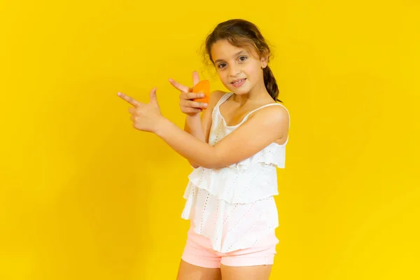 Beyaz Tişörtlü Sevimli Küçük Kız Sarı Arka Planda Yarım Portakal — Stok fotoğraf