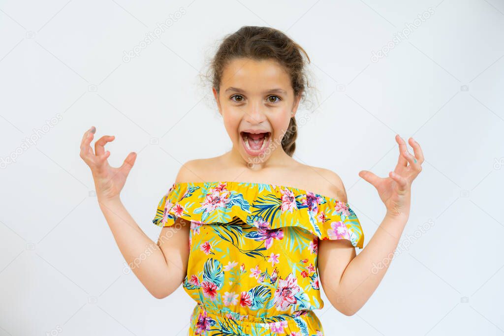 Hispanic little girl crazy and mad shouting and yelling with arms raised. Frustration concept.